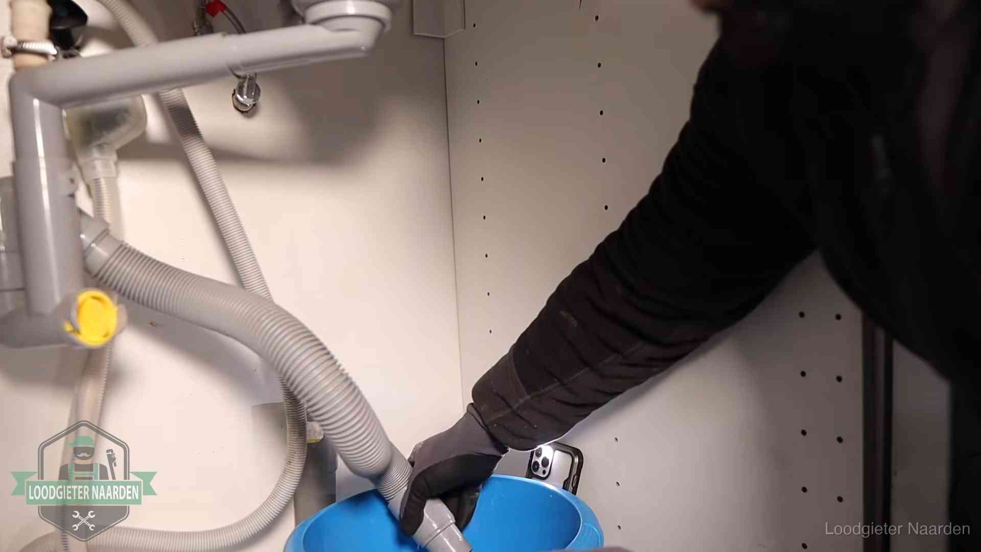 Afvoerslang loopt leeg in een emmer onder de gootsteen in Naarden, een klus die je zelf kunt doen