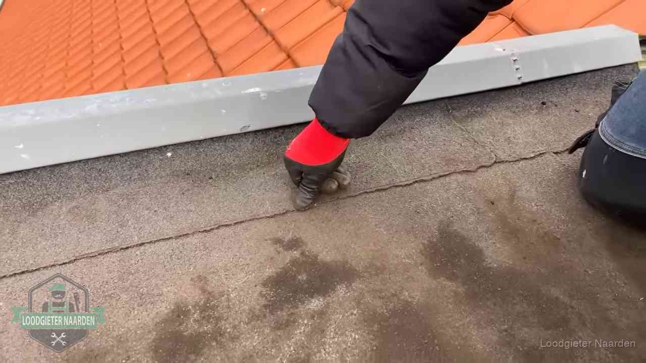 Lekkage bij de naad van een plat dak in Naarden Vakman wijst een naad met vochtplekken aan op een bitumen plat dak in Naarden
