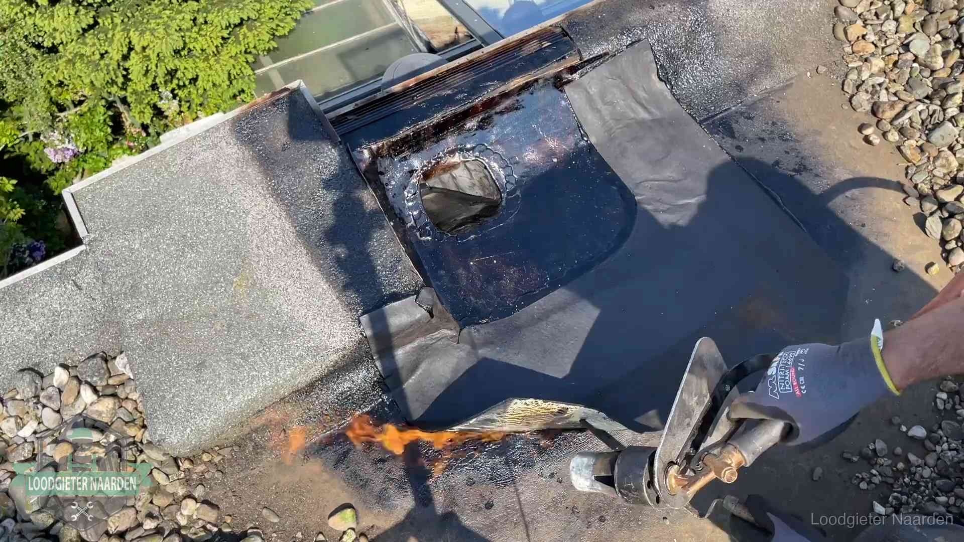 Daklekkage repareren in Naarden Dakdekker brandt bitumen rond een doorvoer tijdens een daklekkage-reparatie in Naarden