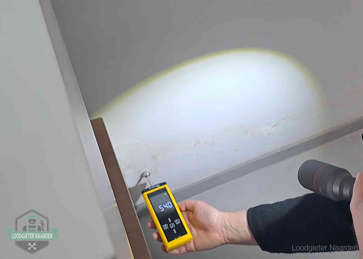 Vochtmeter tegen een natte wand met lekkagesporen in Naarden