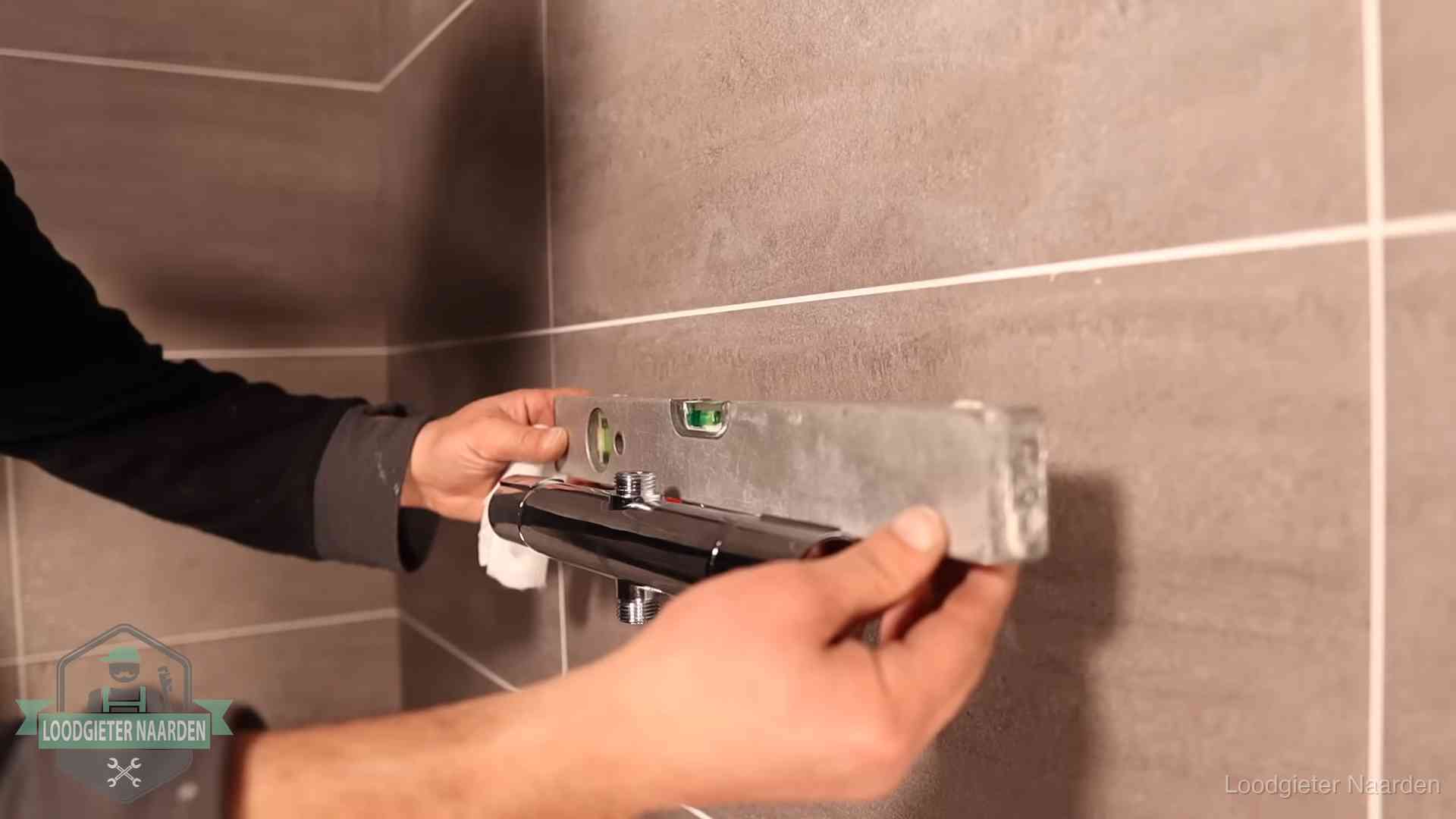 Loodgietersbedrijf voor sanitair in Naarden Loodgieter lijnt een douchekraan uit met een waterpas in een woning in Naarden