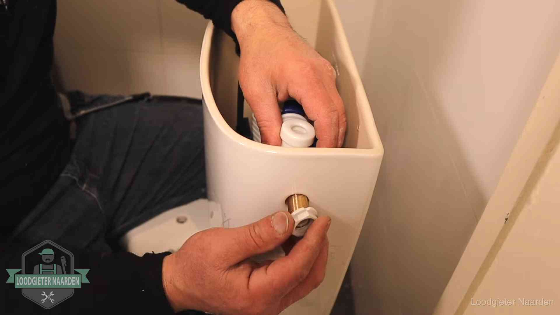 Loodgieter monteert de vlotterkraan van een stortbak bij een toilet in Naarden