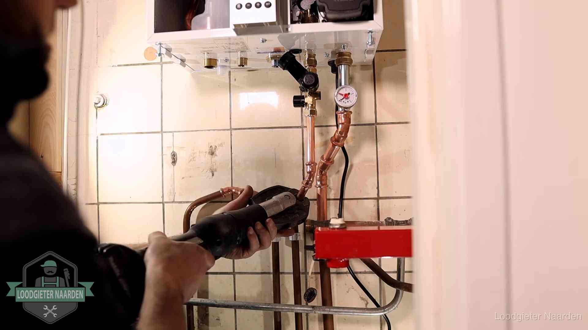 Monteur werkt aan de leidingen onder een cv-ketel in Naarden