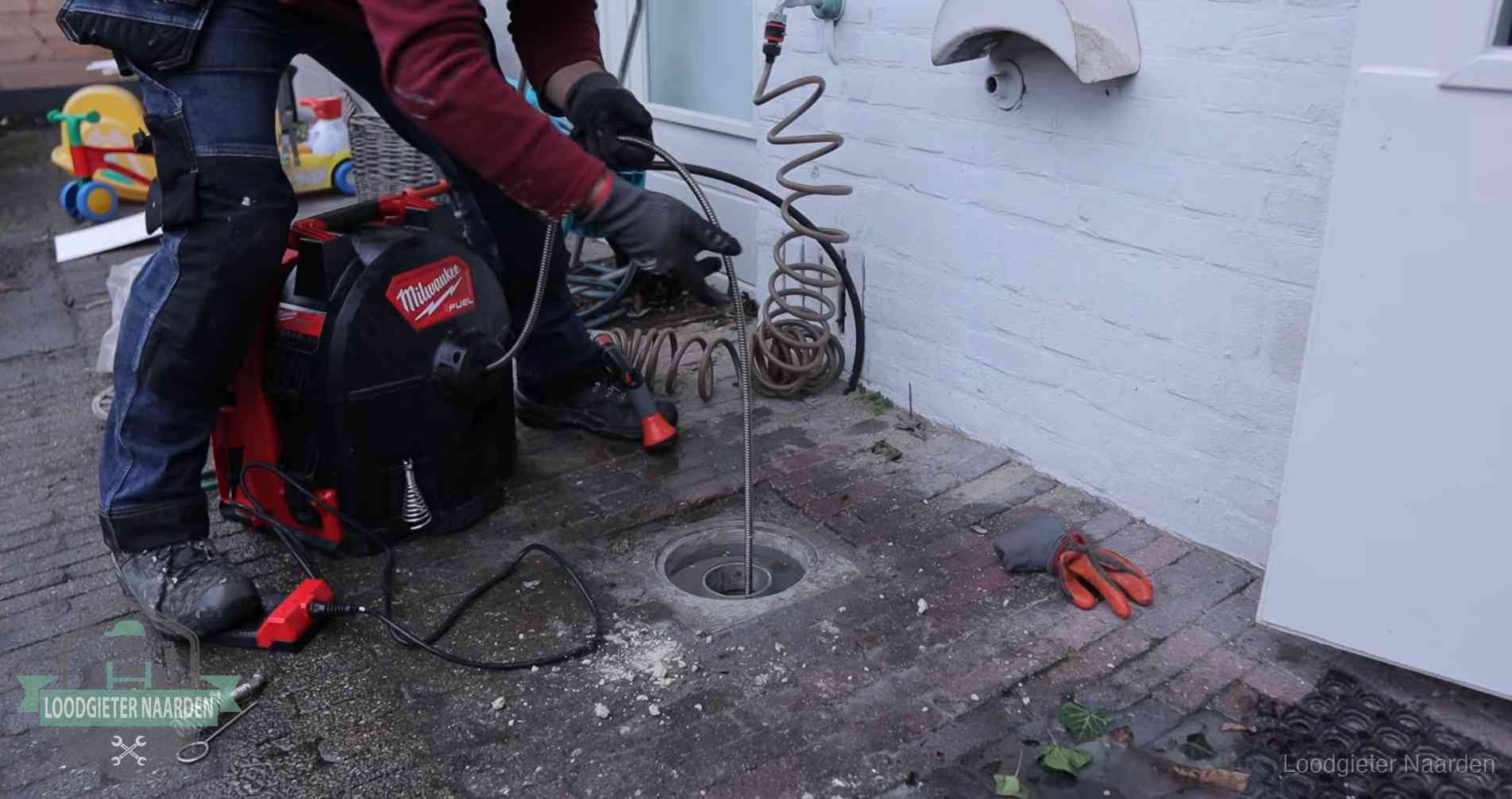 Ontstoppingsputje in de bestrating naast de gevel van een woning in Naarden
