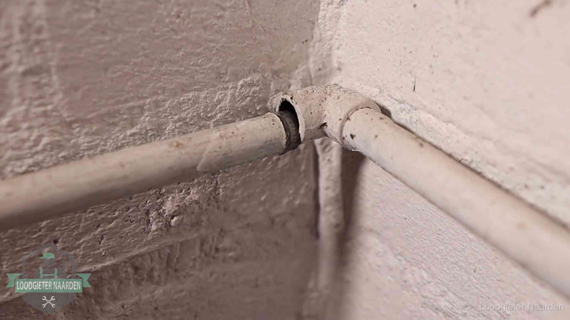 Oude geverfde waterleiding met een losliggende fitting in een woning in Naarden