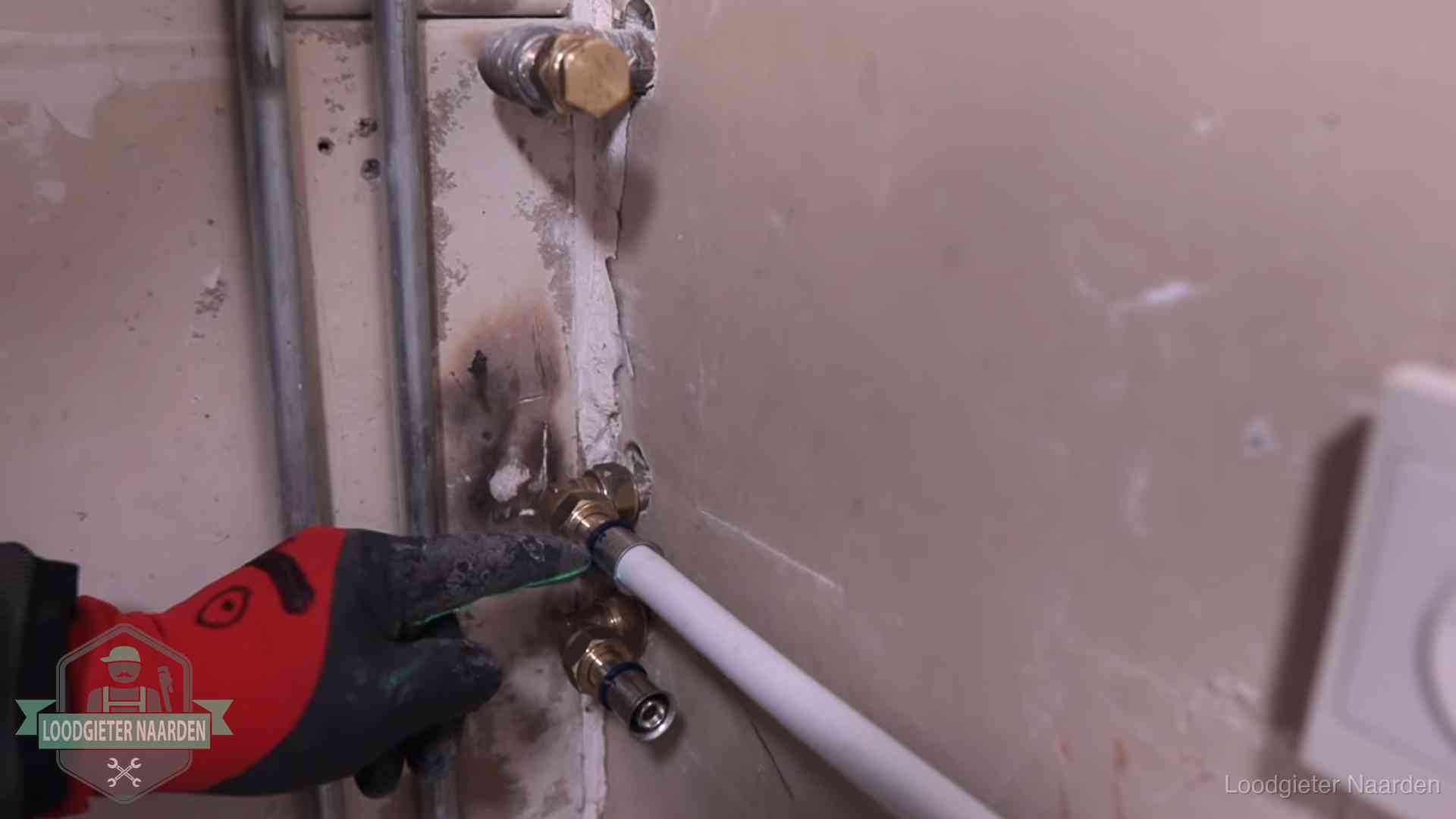 Garantie op loodgieterswerk in Naarden Loodgieter wijst de persfitting op nieuwe muuraansluitingen aan in een woning in Naarden