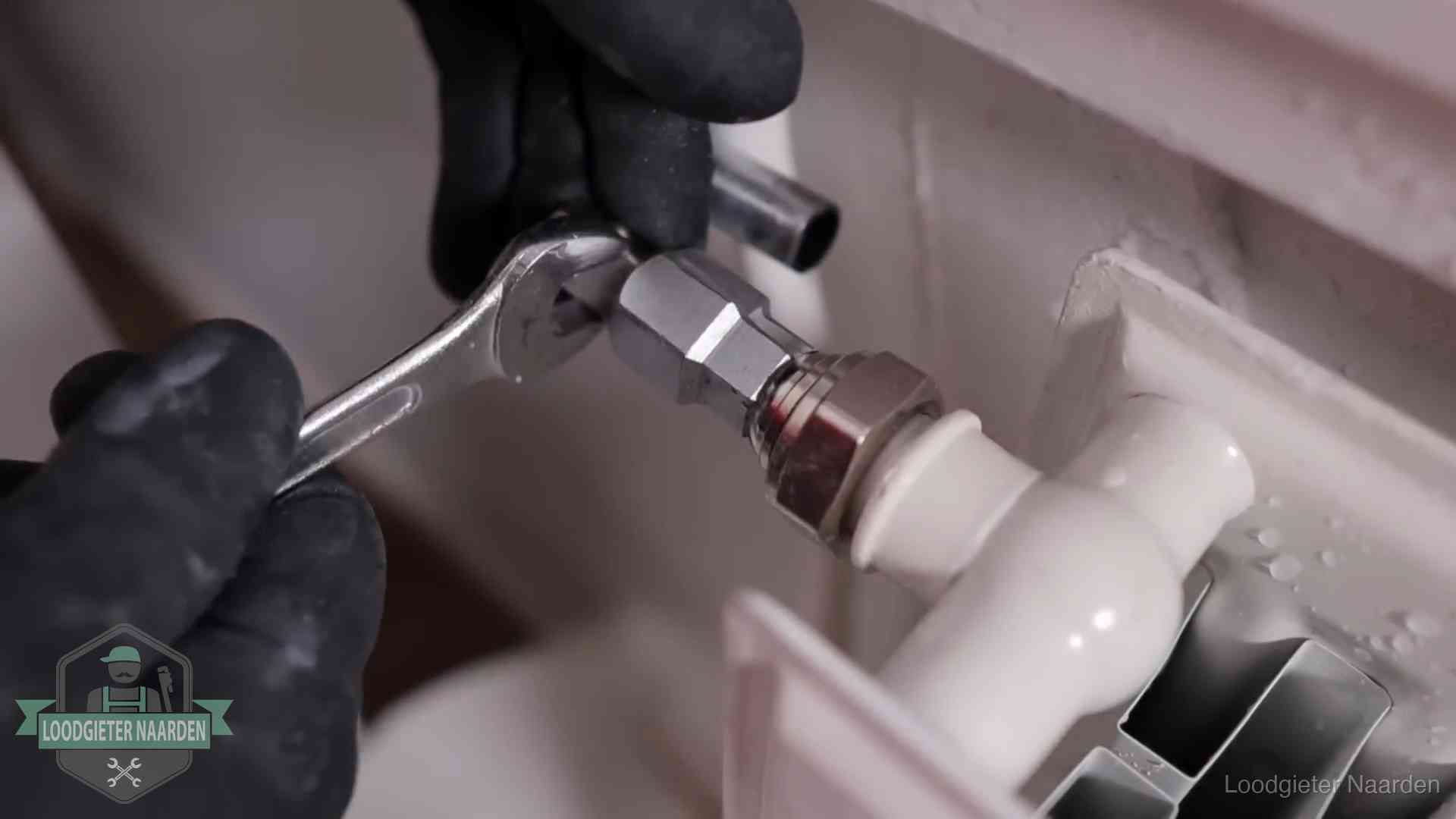 Steeksleutel draait een wartelkoppeling op een radiatorkraan aan in Naarden