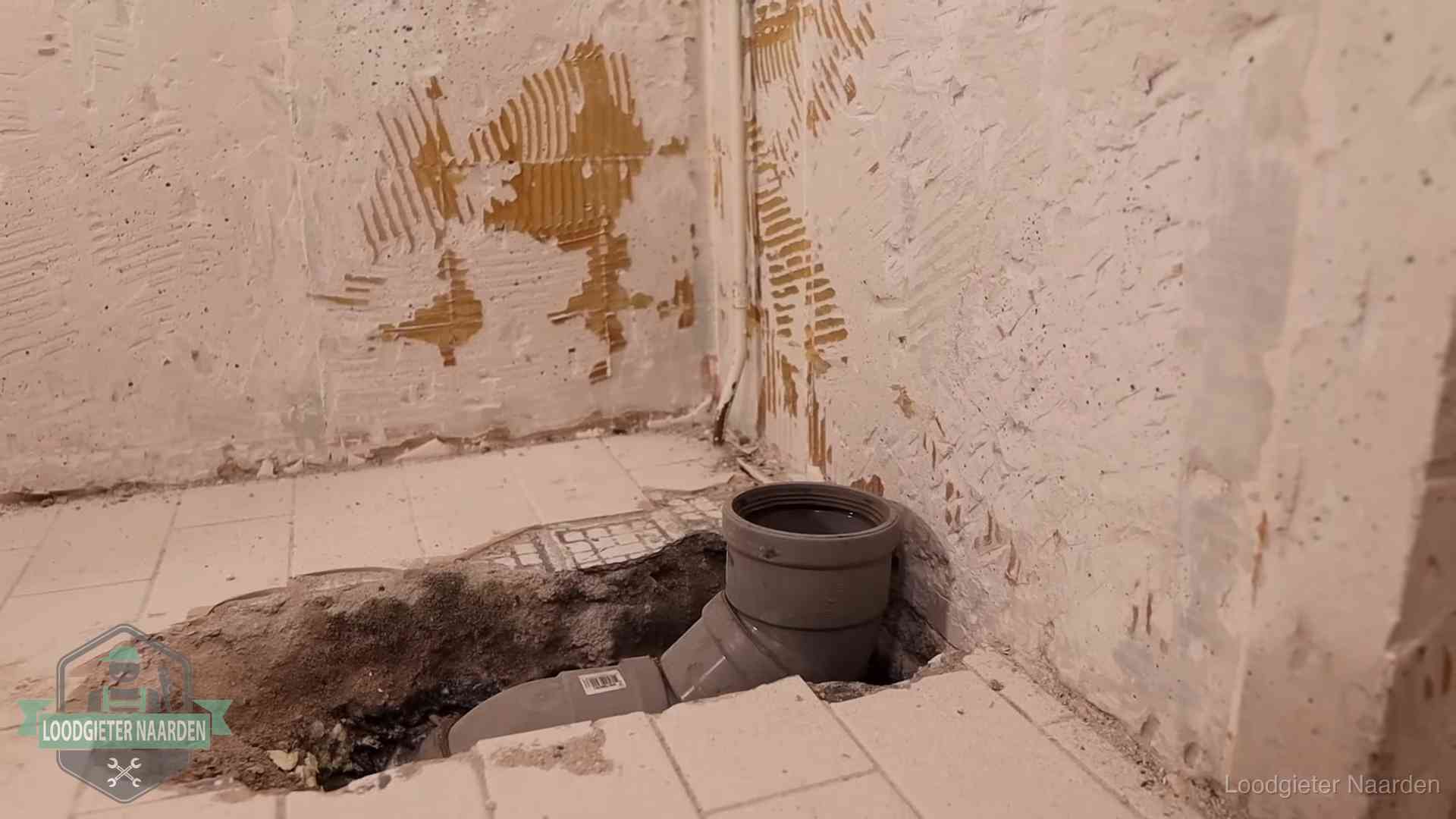 Opengebroken vloer met een nieuwe pvc-rioolbocht in een gegraven sleuf in Naarden