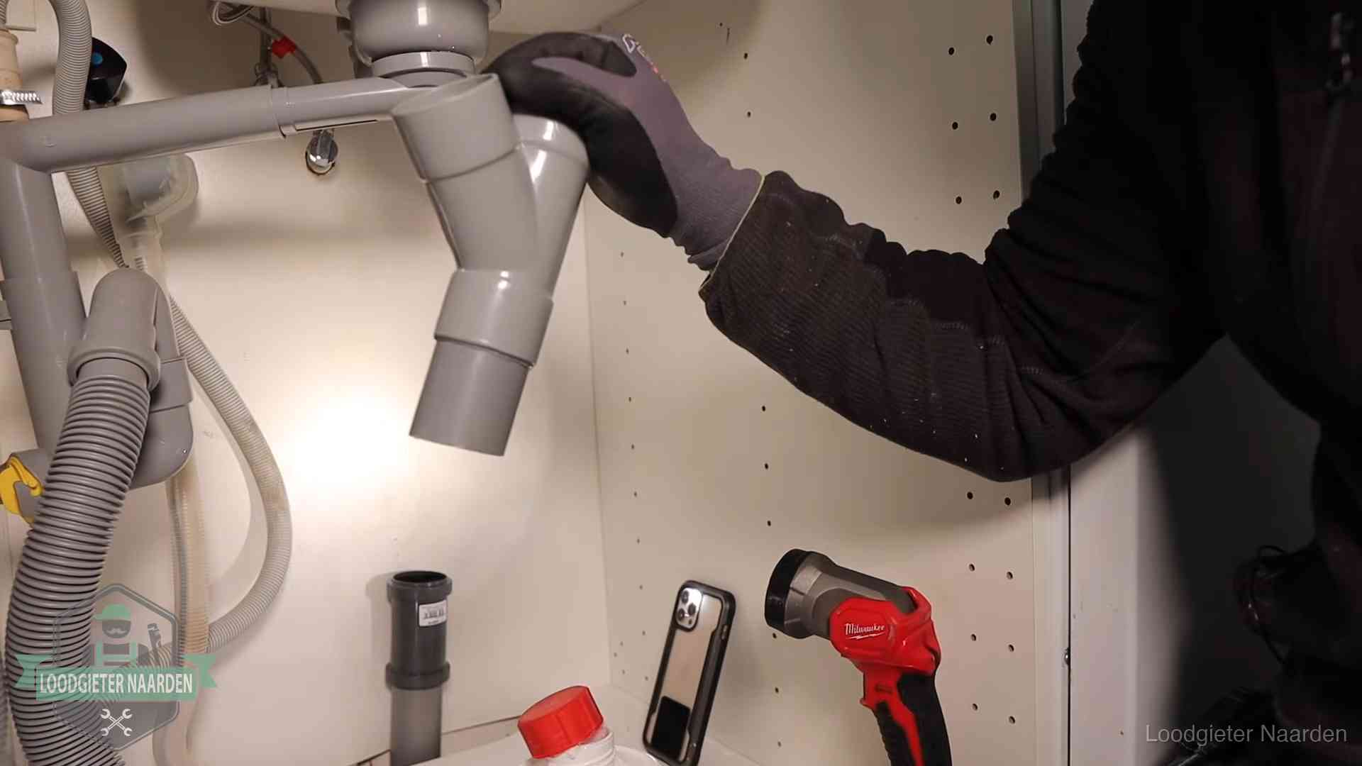 Loodgieter demonteert het sifon- en afvoerwerk onder een gootsteen in Naarden bij stankklachten