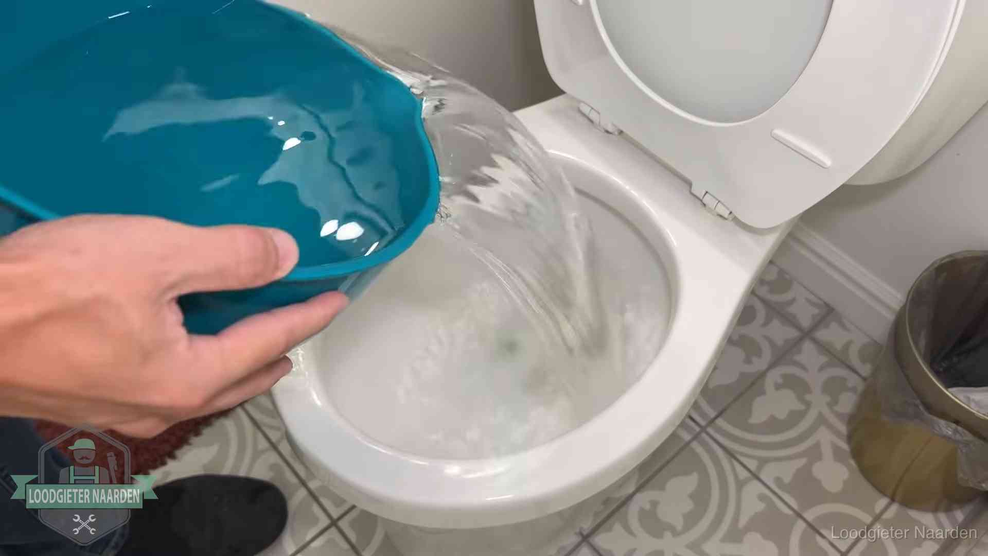 Warm water wordt voorzichtig in de wc-pot gegoten in Naarden