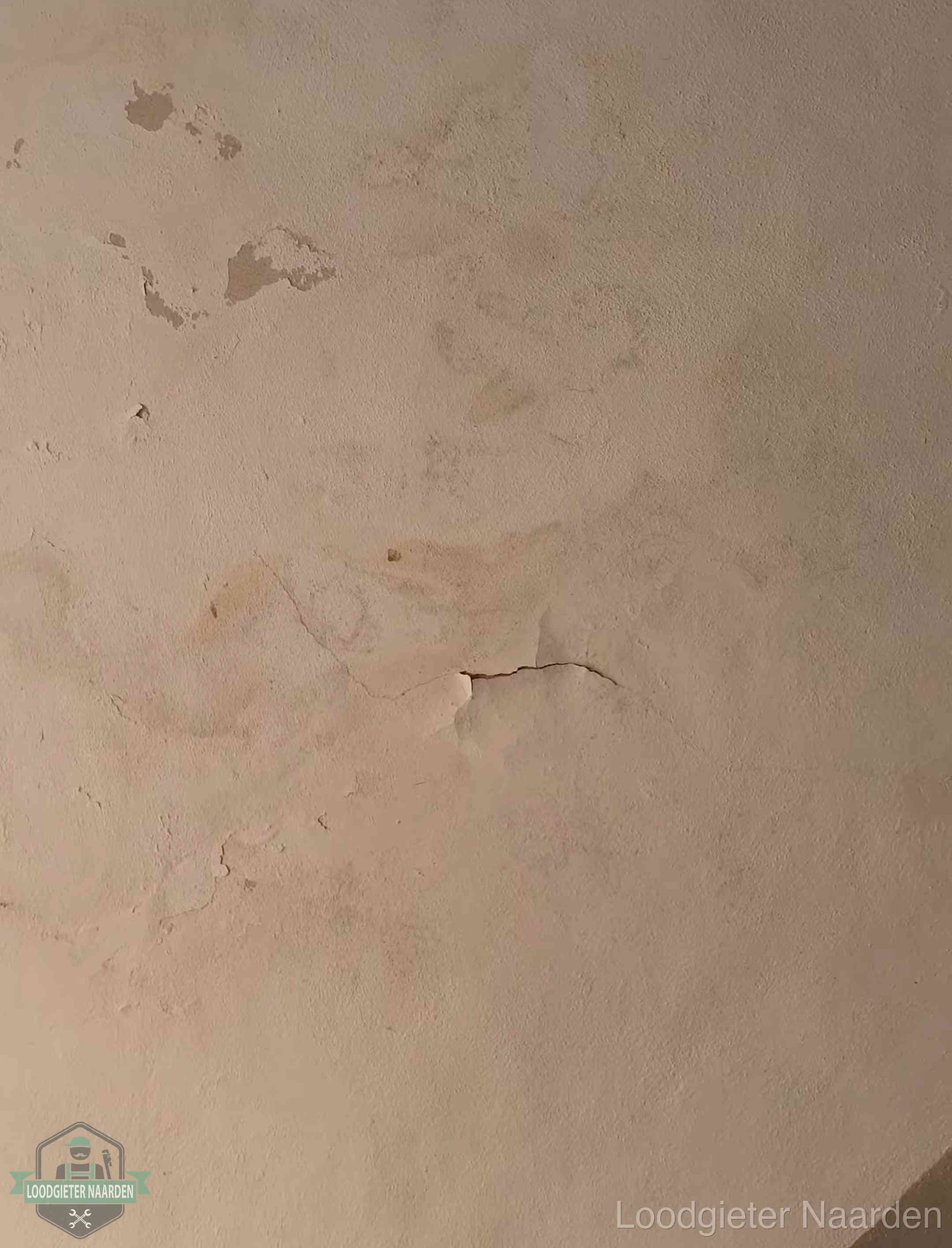 Vochtkringen en afbladderende verf op een plafond in Naarden, schade voor het meetrapport en de verzekering