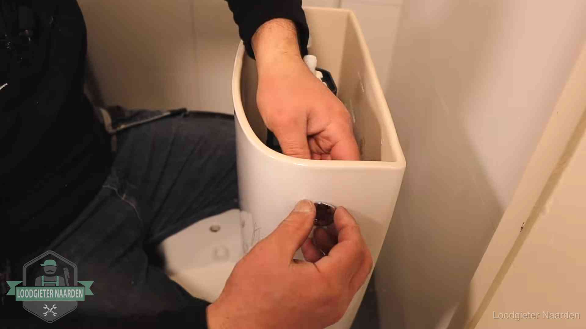 Drukknop van een duoblok-stortbak wordt gemonteerd bij een toilet in Naarden