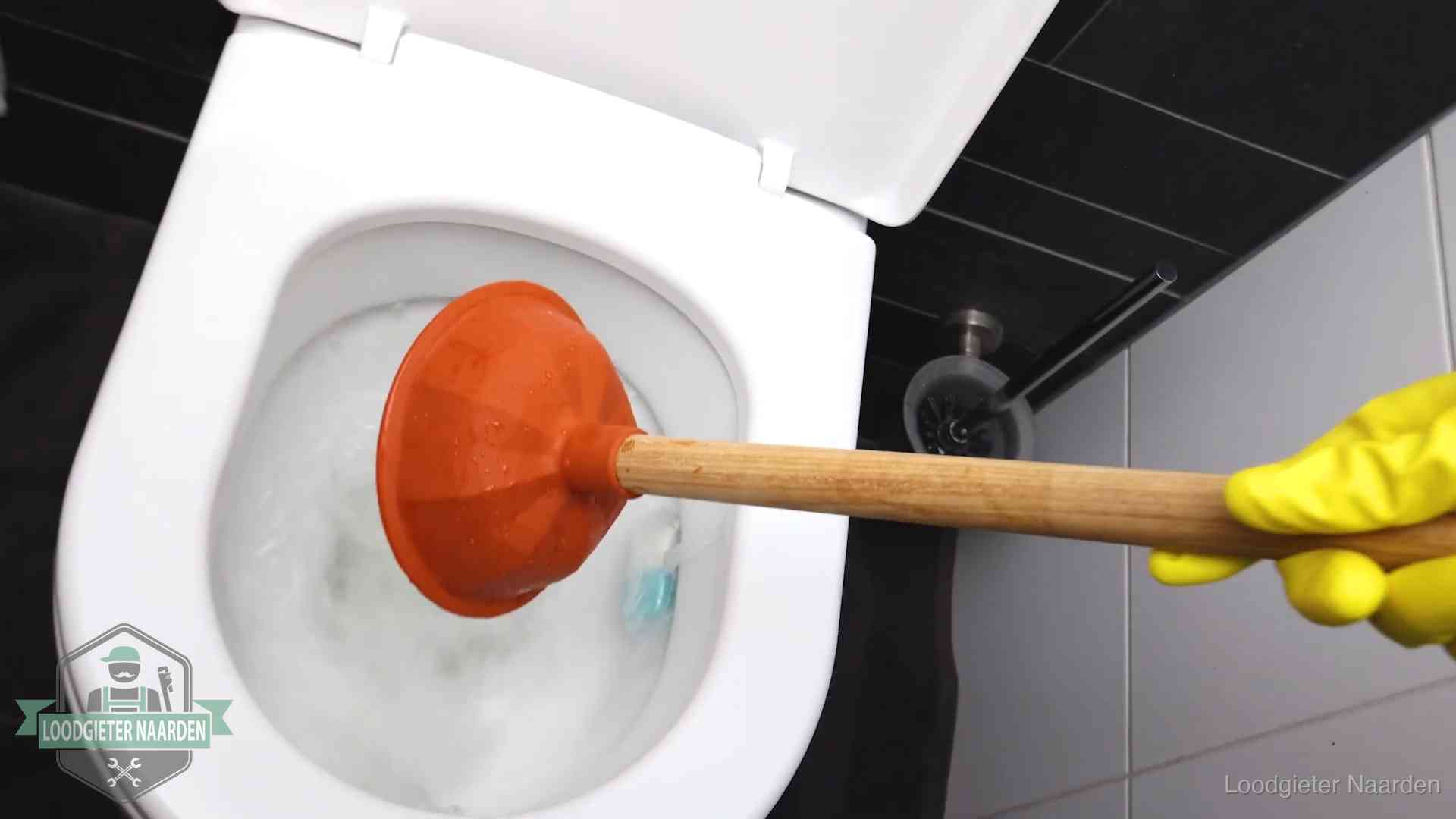 Plopper wordt in de wc-pot gedrukt bij het ontstoppen van een toilet in Naarden